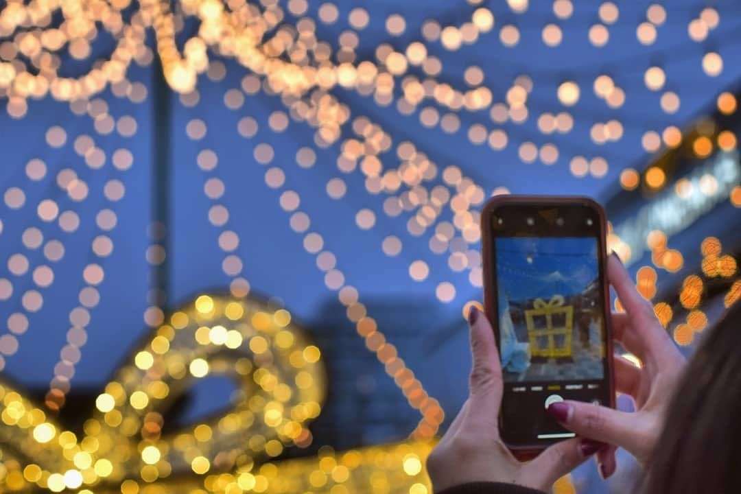 woman taking photo of Christmas lights with her cell phone